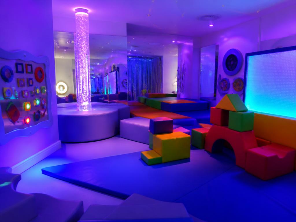 A calm sensory room with a glowing bubble tube and soft play blocks